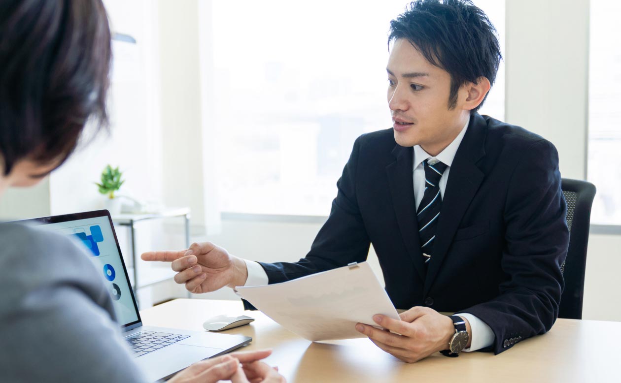 ビジネスミーティング中男性が書類を確認しているシーン