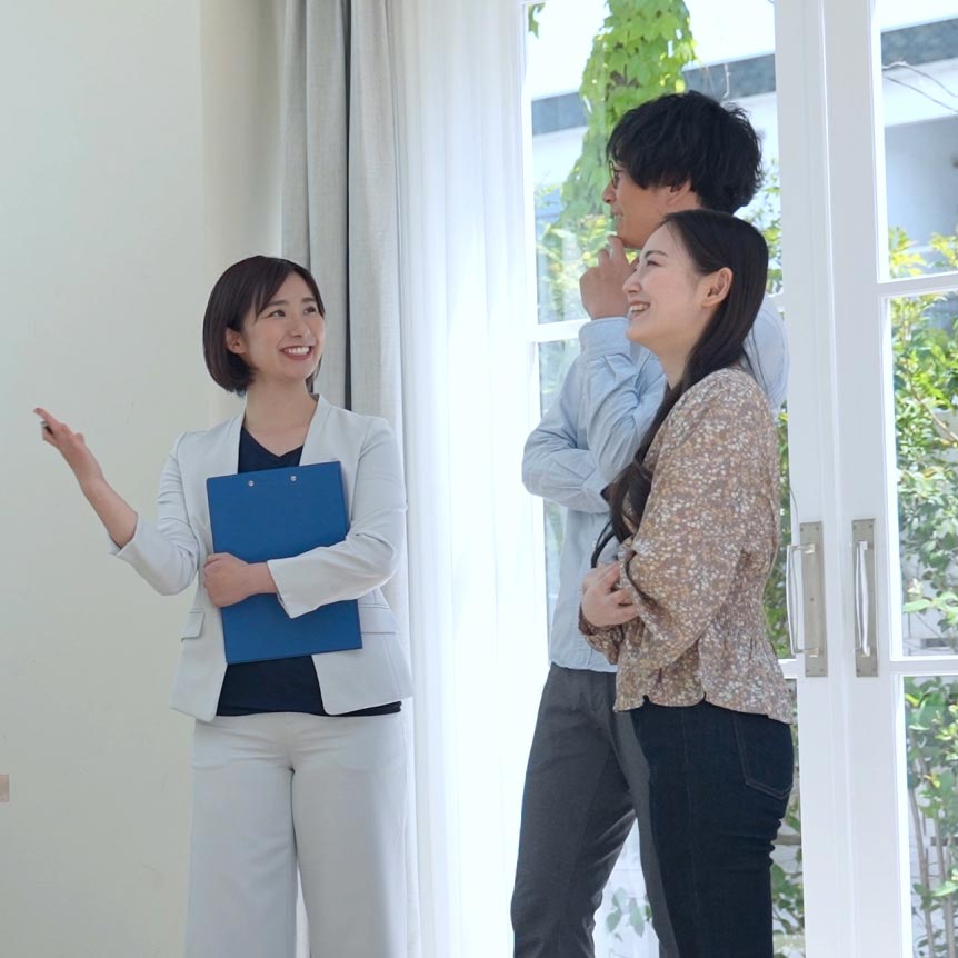 営業担当者が住宅を案内しているシーン、家族と笑顔で会話している様子