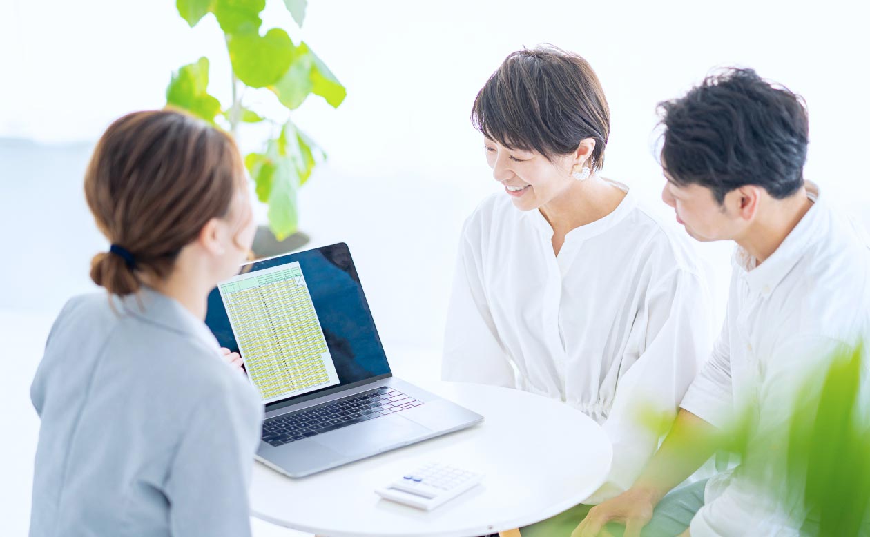 2人の男性と1人の女性がテーブルに座り、パソコンを見ながら会話しているシーン